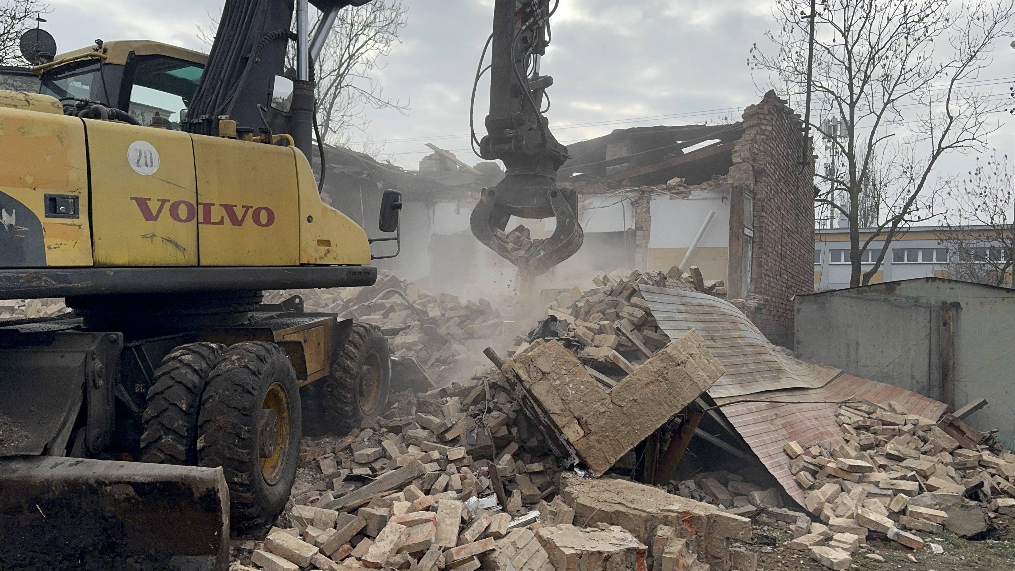Mechaniczna rozbiórka murowanego domu przy użyciu koparki